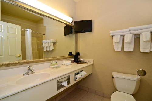 a bathroom with a sink and a toilet and a mirror at Country Inn & Suites by Radisson, Stevens Point, WI in Stevens Point