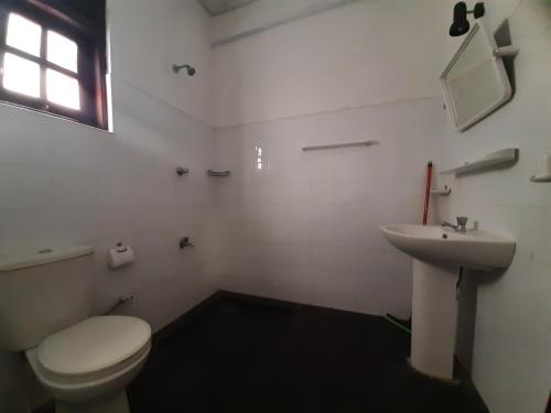a white bathroom with a toilet and a sink at Katagamuwa Rest in Kataragama