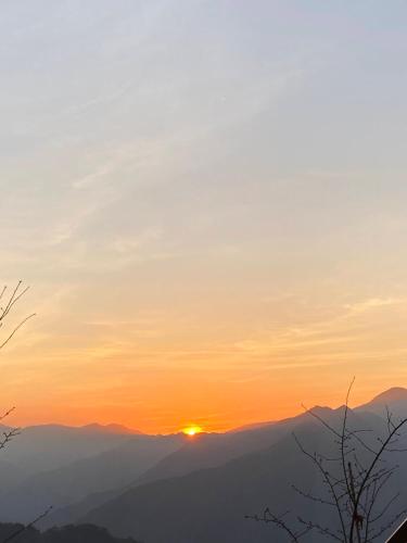 a sunset over a mountain range with the sun in the sky at Tianen Farm in Hualing