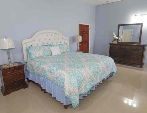 a bedroom with a bed and two dressers and a mirror at Dela de-Rose Guest House Negril Jamaica in Negril