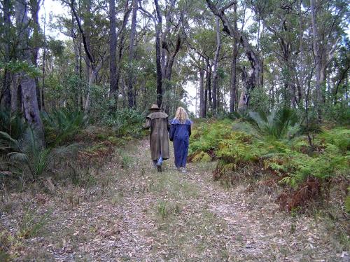 a man and woman walking down a path in the woods at The Bower At Broulee in Broulee