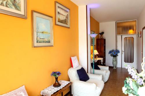 a living room with yellow walls and white chairs at Dallapia in Santa Maria del Piano