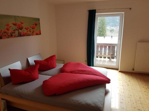 1 dormitorio con 2 camas con almohadas rojas y ventana en SHERPA HAUS Ferienwohnung am Hahnenkamm,Reutte en Hofen