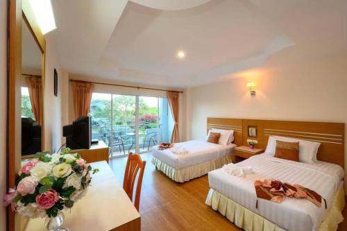 una habitación de hotel con 2 camas y una mesa con flores en Chaikana Thani Hotel, en Phatthalung