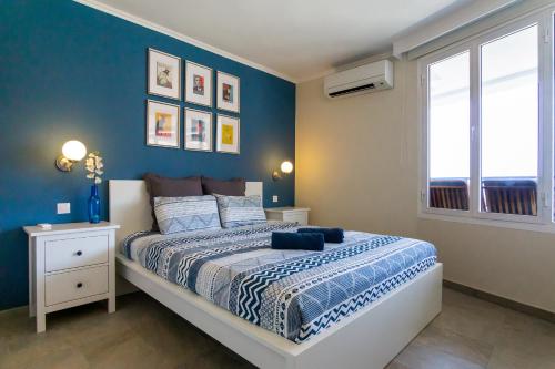 a bedroom with a bed with blue walls and a window at Stunning Views Guaranteed in Taurito