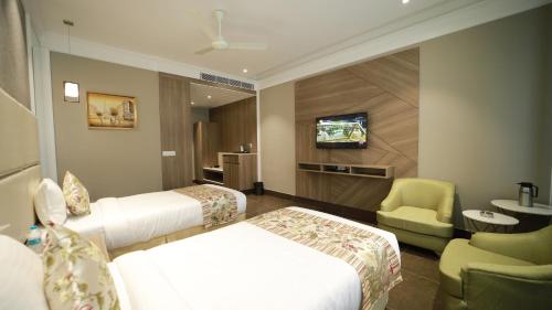 a hotel room with two beds and a tv at THE GRAND VILLAGE in Morādābād