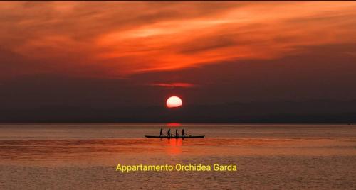a group of people in a boat in the ocean at sunset at Appartamento Orchidea Garda in Garda
