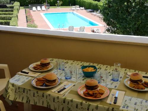 a table with plates of food and a swimming pool at Appartamento Orchidea Garda in Garda