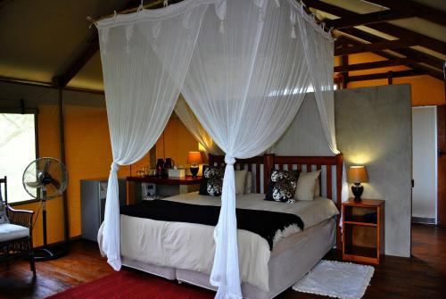 a bedroom with a canopy bed with white curtains at Lion Tree Top Lodge in Guernsey Nature Reserve