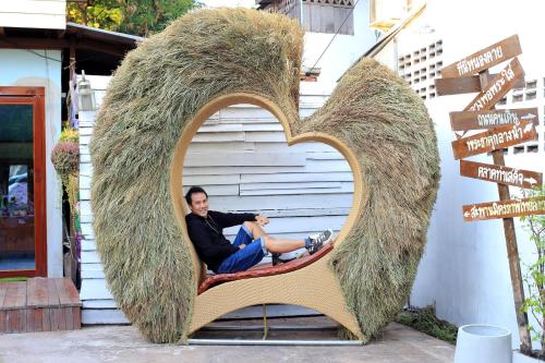 a man is sitting in a heart shaped sign at ฮักเคียงโขง HUG Khieng Khong Nongkhai Hostel in Nong Khai