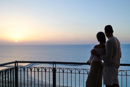 a couple standing on a balcony looking at the ocean at Four Seasons Hotel Alexandria At San Stefano in Alexandria