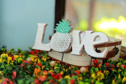 a wooden sign with a pineapple on top of flowers at ฮักเคียงโขง HUG Khieng Khong Nongkhai Hostel in Nong Khai