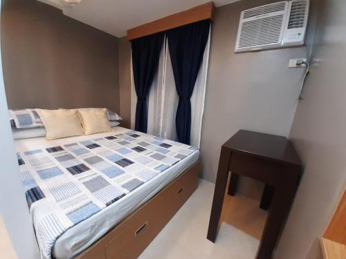 Dormitorio pequeño con cama y mesa en 1Tagaytay, en Lipá