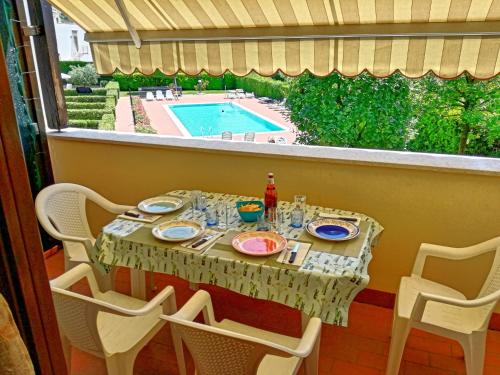 a table and chairs on a balcony with a pool at Appartamento Orchidea Garda in Garda