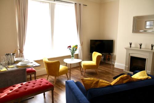 a living room with a blue couch and yellow chairs at Mostyn Villa 2 Free Private Parking in Llandudno