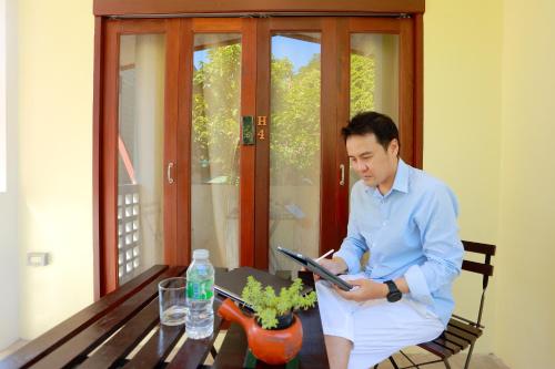 a man sitting on a bench reading a book at ฮักเคียงโขง HUG Khieng Khong Nongkhai Hostel in Nong Khai