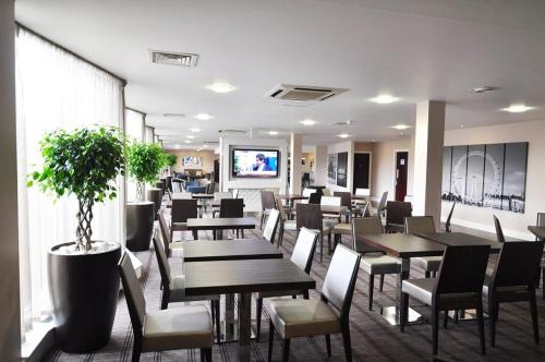 un restaurante con mesas y sillas y una maceta en Holiday Inn Express Royal Docks, an IHG Hotel, en Londres