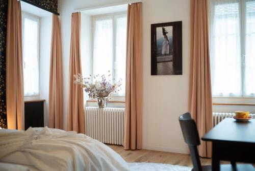 a bedroom with a bed and a table and windows at Gasthof Bären in Schinznach Dorf