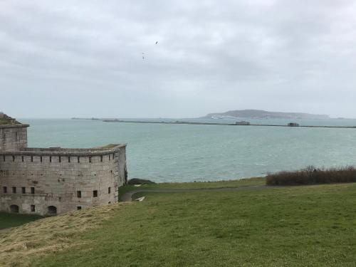 a castle on a hill next to a body of water at A Stones Throw to the Beach :-) in Weymouth