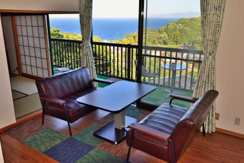 a balcony with a table and chairs and the ocean at Breathtaking View House in Ito