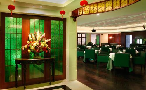 a dining room with green tables and chairs at Seventh Heaven Hotel in Shanghai