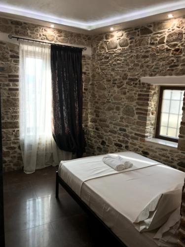 een slaapkamer met een bed en een bakstenen muur bij SAMOS MARIAs' STONE HOUSE 1 in Karlovasi