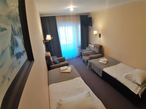 a hotel room with two beds and two chairs at Resort Kasprowy Wierch in Zakopane