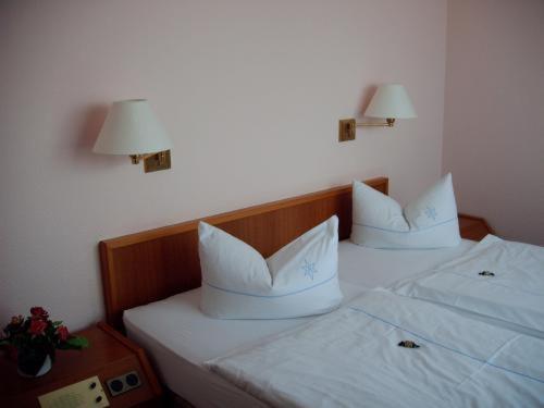 2 camas con sábanas blancas y almohadas en un dormitorio en Hotel Antares, en Oldenburg