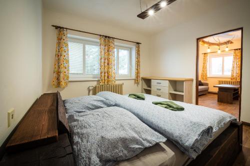 a bedroom with a bed and a desk and windows at Mlyn Tatry in Veľký Slavkov