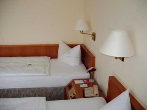 1 dormitorio con 1 cama y mesita de noche con lámpara en Hotel Antares, en Oldenburg