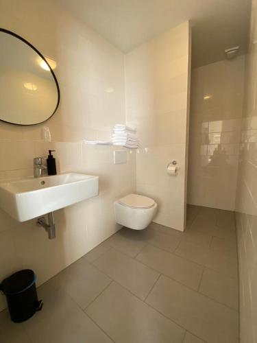 a bathroom with a sink and a toilet and a mirror at Hotel Janssen in Valkenburg