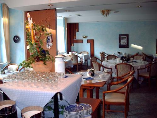 um restaurante com mesas e cadeiras com toalhas de mesa brancas em Hotel Antares em Oldenburg