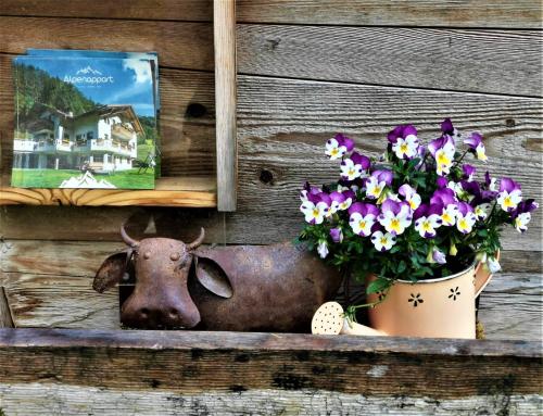 a cow statue and a pot of flowers on a wall at Alpenappart in Cadipietra
