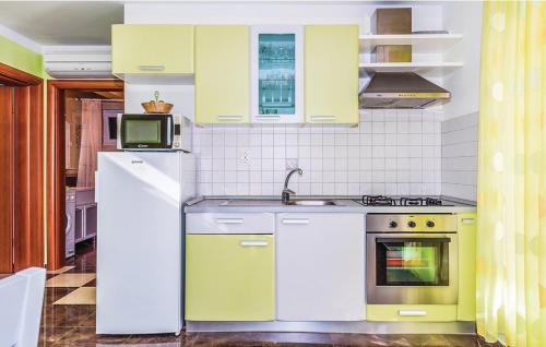 a kitchen with yellow and white cabinets and a microwave at Apartments Hari Tisno in Tisno