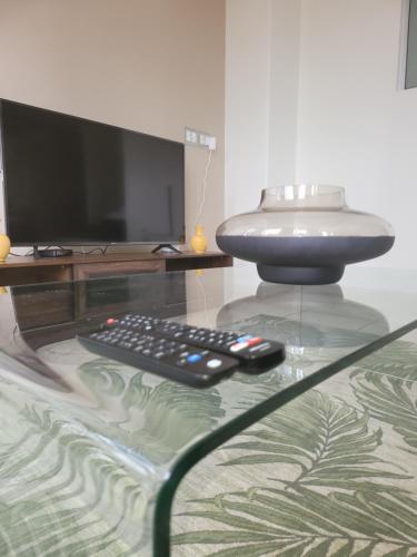 un mando a distancia sentado en una mesa de cristal con TV en The Franklin Luxury Apartments, Unit 1604, en Johannesburgo