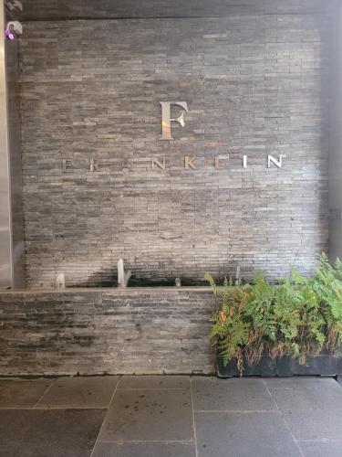 a brick wall with a sign on it with plants at The Franklin Luxury Apartments in Johannesburg