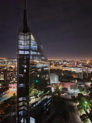 a tall glass building with a city at night at The Franklin Luxury Apartments in Johannesburg