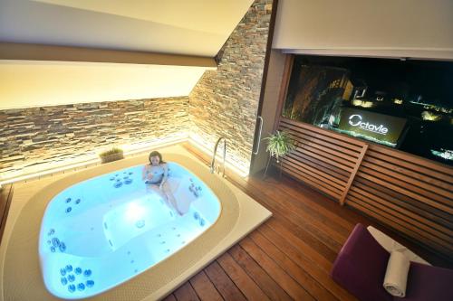 een vrouw in een jacuzzi in een hotelkamer bij Octavie - Suite de luxe à Tournai avec piscine privée, jacuzzi, sauna et hammam in Tournai