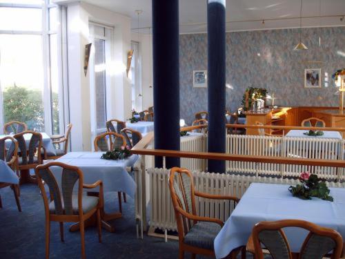 a dining room with white tables and chairs in a restaurant at Hotel Alexander in Oldenburg