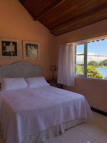 ein Schlafzimmer mit einem weißen Bett und einem Fenster in der Unterkunft Pousada Solar da Praia in Abraão