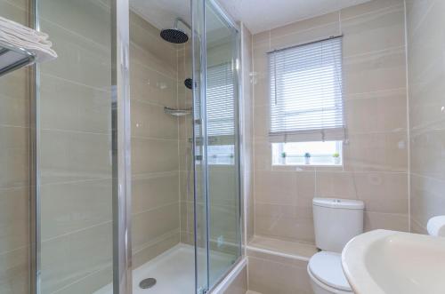 a bathroom with a shower and a toilet and a sink at Kentmere Apartment Thamesmead in Thamesmead