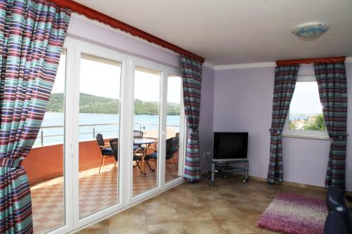 a living room with sliding glass doors and a table with a television at Apartments Hari Tisno in Tisno