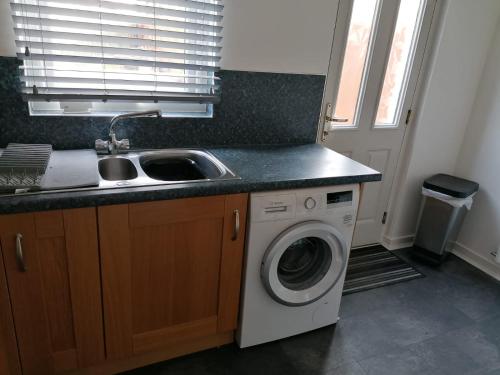a kitchen with a sink and a washing machine at 1 Fulmar Road**Next to West Beach and Golf Course in Lossiemouth