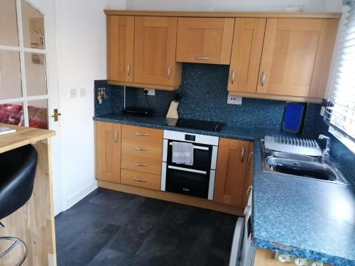 a kitchen with wooden cabinets and a stove top oven at 1 Fulmar Road**Next to West Beach and Golf Course in Lossiemouth