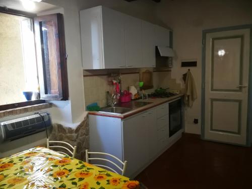 a kitchen with white cabinets and a sink and a window at ALLOGGIO S.ANNA in Isola del Giglio