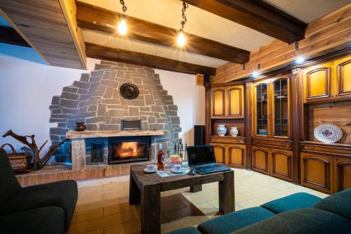 a living room with a stone fireplace with a laptop on a table at Mlyn Tatry in Veľký Slavkov
