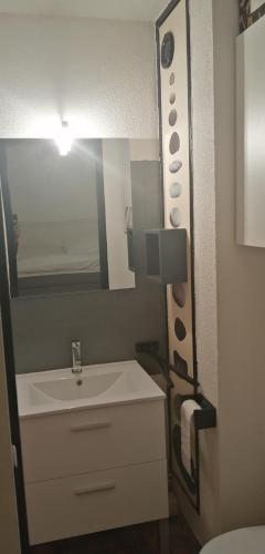 une salle de bain avec un lavabo blanc et un miroir dans l'établissement Le Bora-Bora, à Marseillan