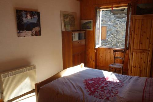 a bedroom with a bed and a window and a chair at Le chalet de Flo in Séez