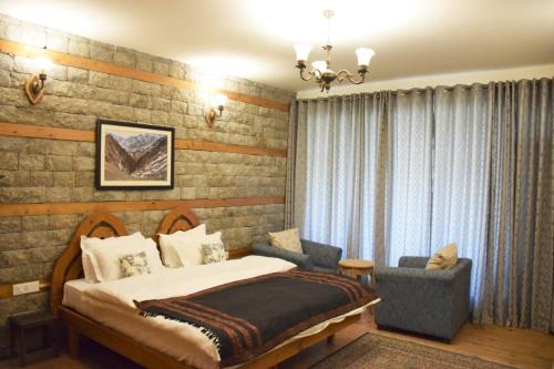 a bedroom with a bed and a chair at Kudrat - A Boutique Homestay- Tirthan Valley in Banjār