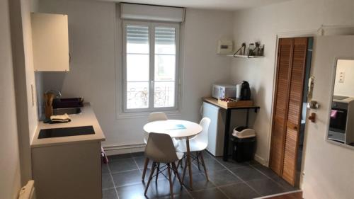 une petite cuisine avec une table et des chaises. dans l'établissement L’été de Mélusine, à Niort